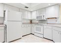 Bright kitchen featuring white cabinets, appliances, and tile flooring, offering a clean and classic design at 3461 Tallywood Cir # 7067, Sarasota, FL 34237