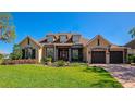 Charming home featuring a stone facade, dormer windows, beautiful landscaping and a brick driveway at 3712 59Th Avenue E Cir, Ellenton, FL 34222
