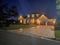 Exterior view of the house at night featuring manicured lawn, dormer windows, and brick-paved driveway at 3712 59Th Avenue E Cir, Ellenton, FL 34222