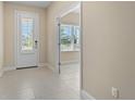 Bright foyer featuring tile flooring, white trim, and a door with sidelight at 3835 Autumn Fern Ter, Sarasota, FL 34243