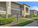 Exterior view of the condo with screened lanai, green grass, and walkway at 5211 Mahogany Run Ave # 126, Sarasota, FL 34241