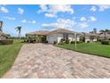 Landscaped home exterior with a brick driveway and lush green lawn under a bright blue sky at 6766 Greenview Ln, Englewood, FL 34224