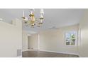 Bright living room featuring modern chandeliers, ceiling fan, stylish flooring, and plantation shutters at 6766 Greenview Ln, Englewood, FL 34224