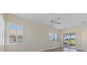 Sun-filled living room with ceiling fan, window shutters, and glass slider to the outdoors at 6766 Greenview Ln, Englewood, FL 34224