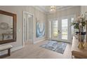 Bright foyer with double glass doors, light wood flooring, and elegant chandelier at 8108 Wild Blue Ter, Sarasota, FL 34241
