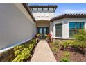Inviting covered front entrance with double doors, stone accents, and lush landscaping at 8108 Wild Blue Ter, Sarasota, FL 34241