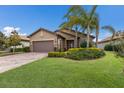 Inviting single-Gathering home featuring manicured lawn, palm trees, and brick-paved driveway at 16719 Ellsworth Ave, Bradenton, FL 34202