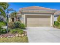 Home exterior featuring a beige garage door, manicured lawn, and mature landscaping at 21037 Anclote Ct, Venice, FL 34293