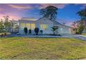 Charming home exterior with a metal roof, well-manicured lawn and landscaping under a gorgeous sunset sky at 2512 Riverside E Dr, Bradenton, FL 34208