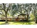 Traditional two story home with manicured front lawn surrounded by mature trees on a sunny day at 411 El Greco Dr, Brandon, FL 33511