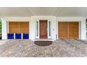 Inviting home entrance featuring a solid wood door, brick pavers, and impact rated garage doors at 516 Kumquat Dr, Anna Maria, FL 34216