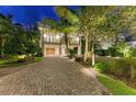 Charming home featuring a brick driveway, lush landscaping, a garage, and a welcoming entrance at 516 Kumquat Dr, Anna Maria, FL 34216