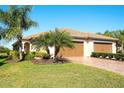 Home exterior showcasing a manicured lawn, mature palms, and a two-car garage at 6638 Willowshire Way, Bradenton, FL 34212