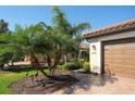Exterior view of a home with a brick driveway, palm trees, and manicured landscaping at 6638 Willowshire Way, Bradenton, FL 34212