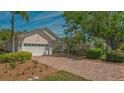 Charming home featuring a brick driveway, lush landscaping, and a well-manicured lawn under a bright, sunny sky at 7133 Victoria Cir, University Park, FL 34201