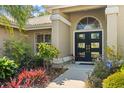 Elegant front entrance with beautiful landscaping and a black double door with glass inserts at 7300 Wax Myrtle Way, Sarasota, FL 34241