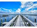 Long wooden pier extending into the tranquil blue water under a partly cloudy sky at 8625 Midnight Pass Rd # 305B, Sarasota, FL 34242