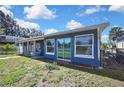 Rear view of a blue home with a walkway leading to a fenced-in yard and sliding glass doors at 14914 Old Dixie Hwy, Hudson, FL 34667