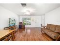 Bright living room featuring laminate floors, a ceiling fan, and a large window bringing in natural light at 1525 Fleetwood Dr, Sarasota, FL 34232
