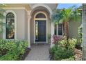 Elegant front entrance with an arched doorway and decorative pillars surrounded by beautiful landscaping at 15508 Leven Links Pl, Lakewood Ranch, FL 34202