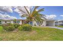 Inviting single-story home featuring lush greenery and a large palm tree in the front yard at 22201 Olean Blvd, Port Charlotte, FL 33952