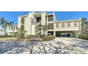 Three story condo with yellow siding, palm trees and covered parking for two cars at 4104 128Th W St # 704, Cortez, FL 34215