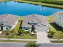 An aerial view showcases a well-maintained house with manicured landscaping near a serene lake at 5744 Woodland Sage Dr, Sarasota, FL 34238