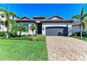 Charming single-story home featuring lush landscaping, a paver driveway, and a two-car garage at 5817 Brandon Run, Bradenton, FL 34211