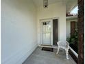 Inviting front entryway featuring a white door with glass accents, a decorative chair, and neutral concrete at 5906 Garden Lakes Majestic, Bradenton, FL 34203