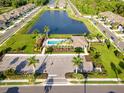 Aerial view of community pool, clubhouse, and surrounding lake, showcasing amenities and neighborhood layout at 5998 Amberly Dr, Bradenton, FL 34208