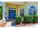 Close up of entryway with decorative blue door, floral wreaths, and manicured landscaping at 6415 Fetterbush Ln, Lakewood Ranch, FL 34202