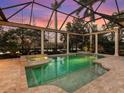 Screened-in pool and spa with stone surround, columns, and an expansive view of the lake at 7921 Waterton Ln, Lakewood Ranch, FL 34202