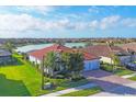 Breathtaking aerial view of a home near the lake, featuring tile roof, green lawn, and mature trees at 13145 Amerigo Ln, Venice, FL 34293