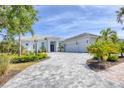 Beautiful one-story home displaying a circular driveway and tropical landscaping at 16419 Kendleshire Ter, Lakewood Ranch, FL 34202