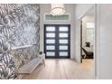 Foyer featuring a statement wall, bench seating, and modern front door at 16419 Kendleshire Ter, Lakewood Ranch, FL 34202