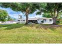 Front view of a cozy home with classic design, shaded by large trees on a green lawn at 3514 Laslo Ave, North Port, FL 34287