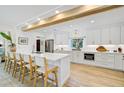 Bright, modern kitchen boasts white cabinetry, stainless appliances, breakfast bar, and hardwood floors at 400 Nokomis S Ave, Venice, FL 34285
