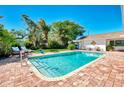Inviting pool with brick-paved patio, lush landscaping, and ample seating at 400 Nokomis S Ave, Venice, FL 34285