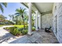 Inviting covered patio with stone flooring and classic white pillars and a rocking chair at 4002 Las Palmas Way, Sarasota, FL 34238