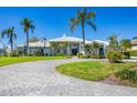 Elegant home featuring a circular driveway and lush tropical landscaping with palm trees at 4002 Las Palmas Way, Sarasota, FL 34238