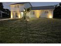 Inviting home with exterior lights, well-manicured lawn, and tidy landscaping at dusk at 5104 Silver Bell Dr, Port Charlotte, FL 33948