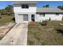 Two-story home with a concrete driveway, an attached garage, and simple landscaping elements at 5104 Silver Bell Dr, Port Charlotte, FL 33948