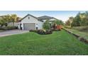 Attractive home with a well-manicured lawn, mature trees, and a paver driveway leading to a three-car garage at 5203 Rushmere Ct, Palmetto, FL 34221