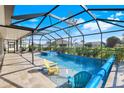 Screened-in swimming pool with lounge chairs and a hot tub for relaxing outdoor living at 566 Corrientes Cir, Punta Gorda, FL 33983