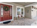 Inviting front porch with a brick floor, bench, and a decorative wreath on the front door at 6913 Neopolitan Ct, Apollo Beach, FL 33572