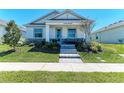 Charming single-story home with a manicured lawn, stone accents, and welcoming front porch with outdoor seating at 7712 Saloon Ln, Sarasota, FL 34240