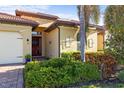 Inviting single-story home showcasing a tile roof, lush landscaping, and an elegant wood front door at 108 Maraviya Blvd, Nokomis, FL 34275