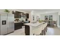 Modern kitchen features stainless steel appliances, dark cabinets, and a large island with seating at 10853 Gentle Current Way, Parrish, FL 34219