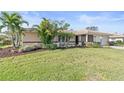 Beautiful single-story home with lush landscaping, mature palm trees, and well-manicured green lawn at 128 Da Vinci Dr, Nokomis, FL 34275