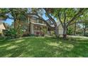View of the well-manicured lawn, mature trees and a two-story brick home with a covered porch at 1533 Oak Way, Sarasota, FL 34232